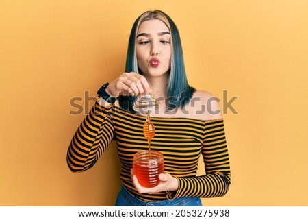 Young modern girl holding honey making fish face with mouth and squinting eyes, crazy and comical. 