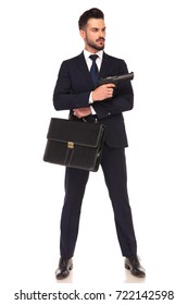 Young Modern Hitman Showing His Gun While Standing With Suitcase On White Background