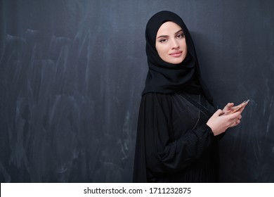 Young Modern Muslim Business Woman Using Smartphone Wearing Hijab Clothes In Front Of Black Chalkboard