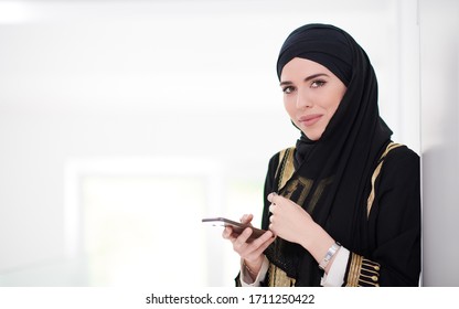 Young Modern Muslim Business Woman Using Smartphone Wearing Traditional Hijab Clothes At Home