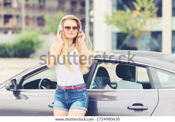 Young modern woman having fun listening music\
on wireless headphones in city – smiling girl enjoy song vibes on\
headsets – carefree urban teen listen radio outdoor alone due to\
social distancing