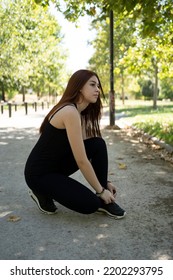 Young Modern Woman Tying Running Shoes In Urban Park.