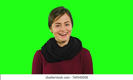 A young modest lady smiling and looking down against a green background. Medium shot - Powered by Shutterstock