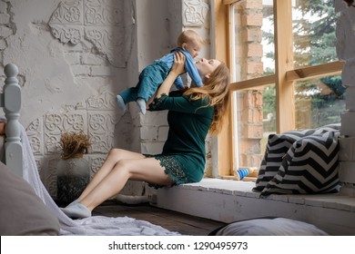 Young mom and beautiful baby sitting on the windowsill and playing. - Shutterstock ID 1290495973