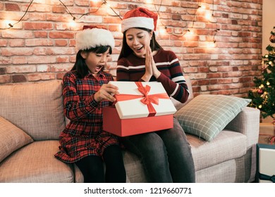 Young Mom Buying Present On Online Shop On Christmas Sale. Two Girls Excited Open The Gift From Internet Store On Boxing Day. Family Surprised By The Thing Inside The Red Box.