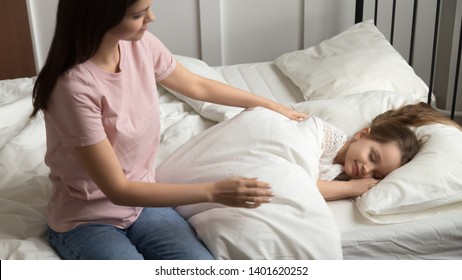 Young Mom Caress Stroke Little Cute Daughter Take Her To Cozy Bed For Day Or Night Sleep, Loving Mother Comfort Small Girl Child Taking Peaceful Nap In Soft Comfortable Mattress In Home Bedroom