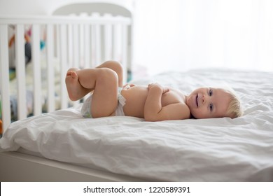 Young Mom, Changing Baby Diaper After Bath In Sunny Bedroom