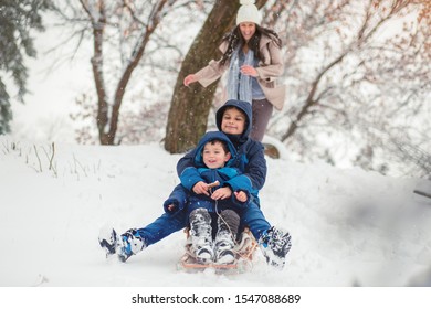 Young Mom Chasing Her Cute Sons While They Are Sledding