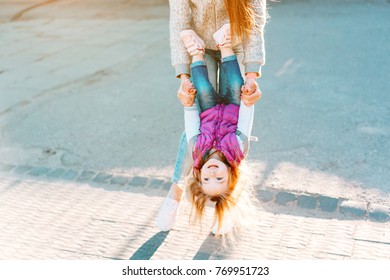 Young mom and cheerful adorable blond girl playing, having fun