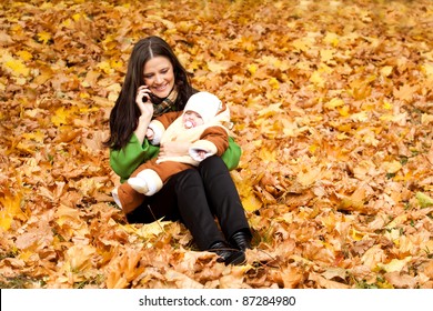 Young Mom With Child In Hand And Talk On Cell Phone