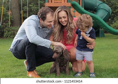 Young Mom And Dad Introduce Toddler To Family Dog In The Back Yard Smiling