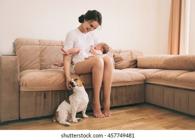 Young Mom With Her Cute Baby Playing With Jack Russel Terrier Dog. Breastfeeding Mother. Family And Pet At Home.