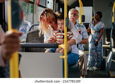 A Young Mom And Her Son Are Riding In A City Bus