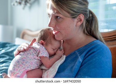 Young mom holding baby girl and patting her back - Shutterstock ID 1697432050