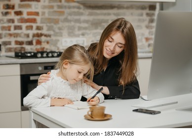 A young mom is hugging a pretty daughter while she is drawing in the notebook at home. A gorgeous mother is looking at her blonde child which is doing homework. - Powered by Shutterstock