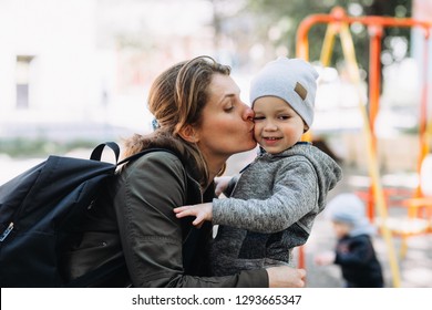 Young Mom Is Kissing Her Beautiful Child In The Playground