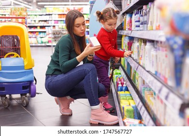 Young Mom With Little Daughter Choosing Children's Cosmetics At Supermarket Store