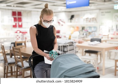 Young Mom With Newborn In Stroller Shopping At Retail Furniture And Home Accessories Store Wearing Protective Medical Face Mask To Prevent Spreading Of Corona Virus. New Normal During Covid Epidemic.