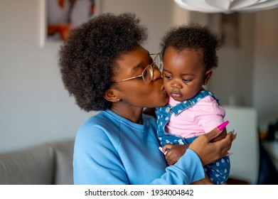 A Young Mom Posing On Camera With Her Baby And Kissing Him