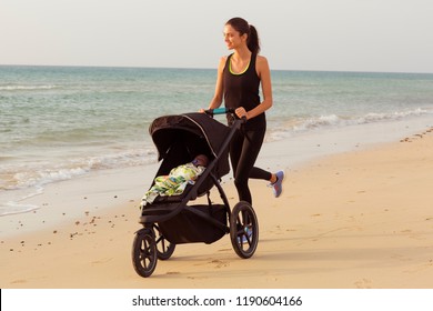 Young Mom Is Running With Stroller On The Beach.