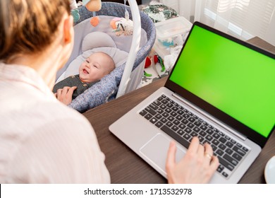 Young mom shopping online on clothing website using laptop. Woman searching for apparel on-line. Son and mummy working from home. Boy playing on the background. Close-up. Back view. Focus on baby.