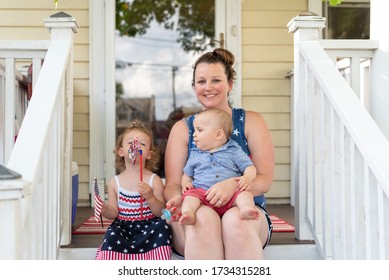 Young Mom And Two Little Kids Celebrating The Fourth Of July At Home On The Front Porch