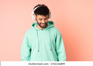 Young Moroccan man isolated on pink background listening music - Powered by Shutterstock