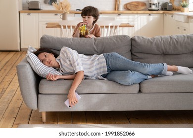 Young Mother Annoyed With Hyperactive Kid. Depressed Woman Mom Or Nanny Lying On Couch Stressed With Noise And Son Bad Behavior. Exhausted Tired Mommy Need Rest. Misbehave Child And Parenthood Routine