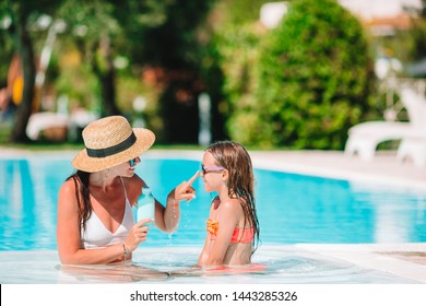 Young mother applying sun cream to kid nose in swimming pool - Powered by Shutterstock