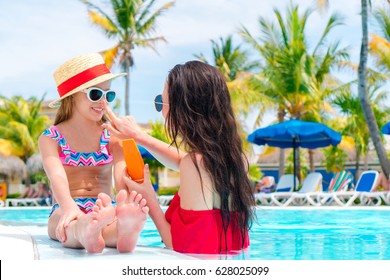 Young Mother Applying Sun Cream To Kid Nose In Swimming Pool