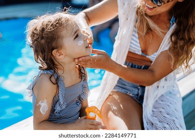 Young mother applying sunscreen lotion to her daughter. Safety sunbathing in hot day. - Powered by Shutterstock