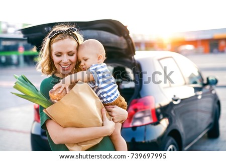Young mother with baby boy in front of a supermarket.