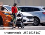 A young mother with a baby carriage in the parking lot