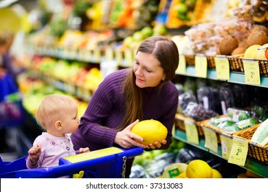 Young Mother With Baby Daughter Shopping In Supermarket