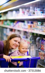 Young Mother With Baby Daughter Shopping In Supermarket