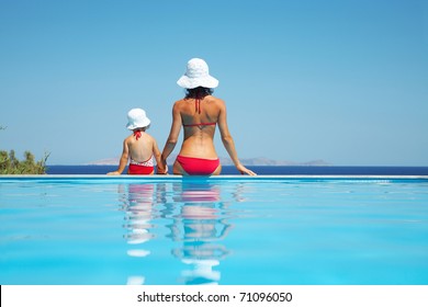 Young mother with baby daughter sitting on the edge of the pool and stare at the sea - Powered by Shutterstock