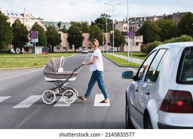 Young mother with the baby pram is walking by the crosswalk. Concepts of safety and traffic code.