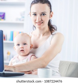 Young Mother And Baby Using Laptop To Communicate With Grandma Via Skype