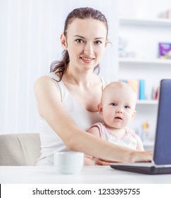 Young Mother And Baby Using Laptop To Communicate With Grandma Via Skype