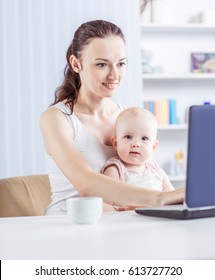 Young Mother And Baby Using Laptop To Communicate With Grandma Via Skype