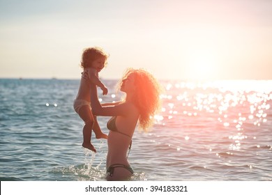 Young Mother In Bikini Standing Swimming And Playing With Male Child Boy In Sea Or Ocean Water Sunny Day Outdoor On Natural Background, Horizontal Picture