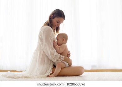 Madre joven amamantando a su bebé recién nacido en casa