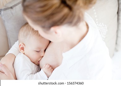 Young mother breastfeeding the newborm baby - indoors 