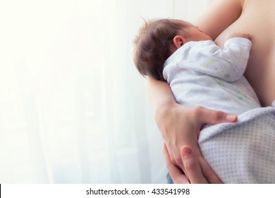 Young mother breastfeeding newborn baby.