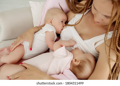 Young mother breastfeeding newborn twins sitting in a chair
