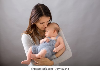 Young Mother, Caressing Her Newborn Baby Boy, Holding Him In Her Arms And Smiling From Happiness