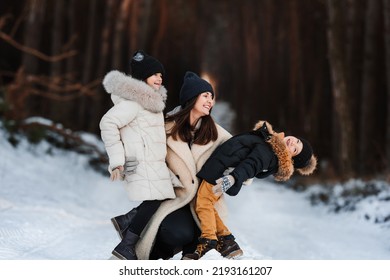 Young Mother With Children On Vacation In Winter Park. Happy Family Spending Time Together.