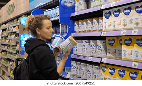 Young Mother Choosing Baby Formula For Her Newborn. Picking Different Options From The Shelf And Reading The Labels. Warsaw-Poland-November 2021