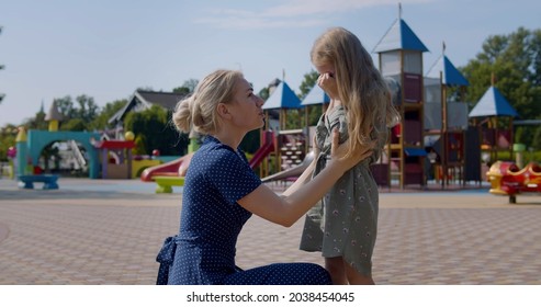 Young Mother Comforting Her Upset Daughter At Playground. Side View Of Worried Mom Hug And Calm Down Unhappy Crying Child Outdoors