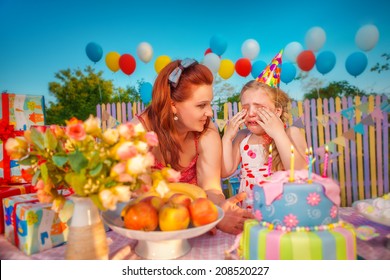 Young Mother Comforts Crying Baby Girl In Birthday Hat, Which Throwing A Tantrum  